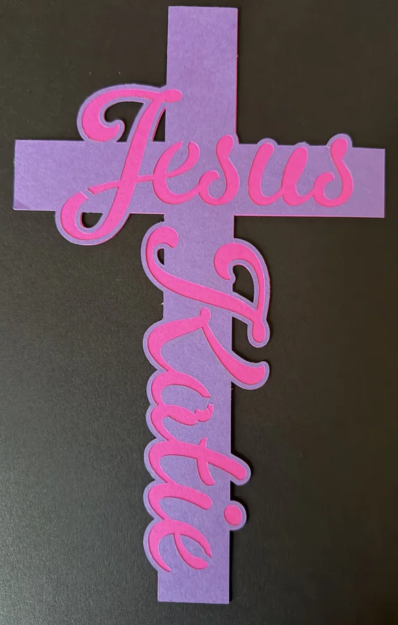 Two-layer name cross: pink Jesus and Katie on top of a purple cross